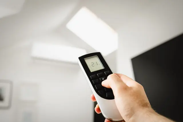Person using a smartphone near a smart home thermostat display