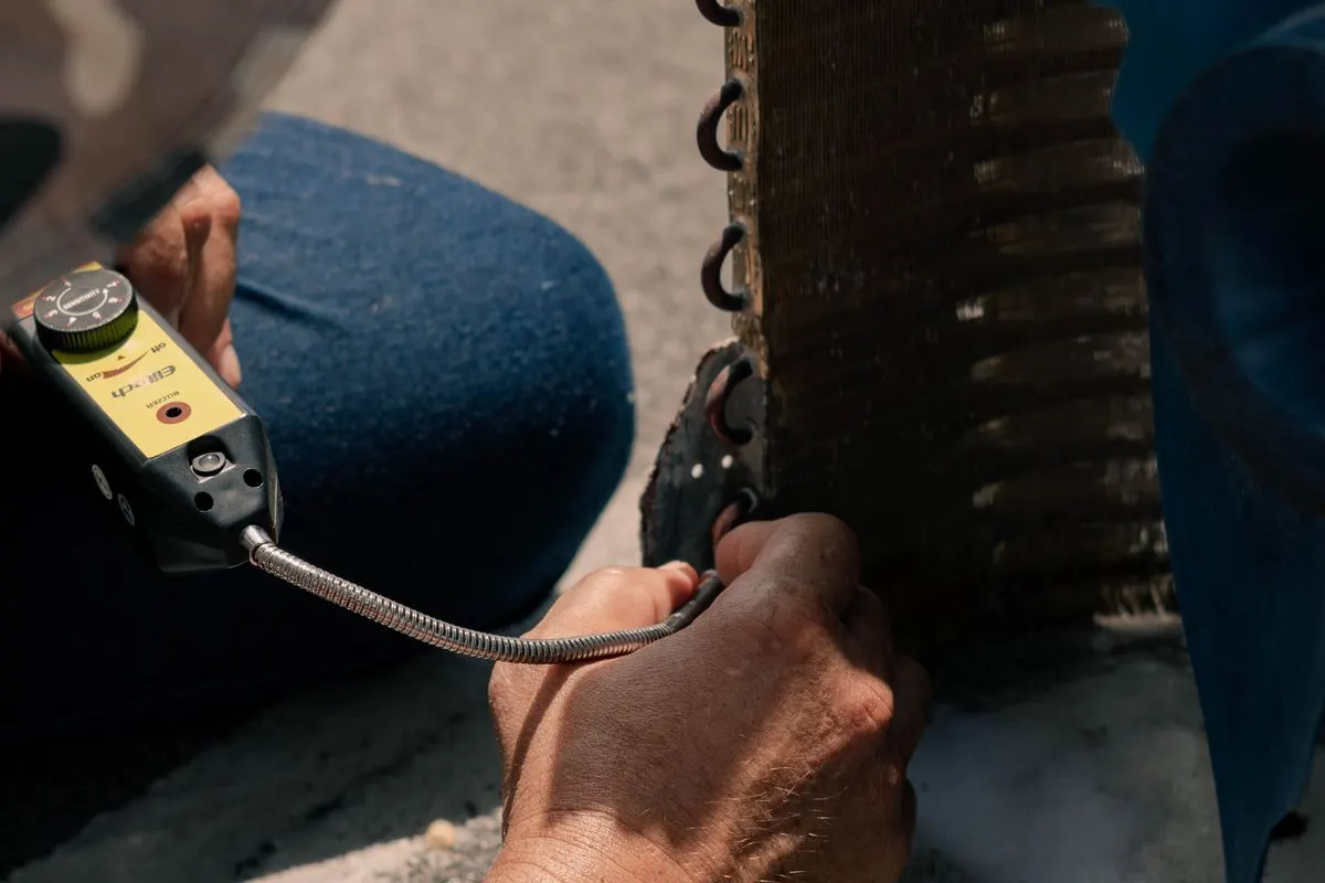 Technician using tools while servicing an air conditioner coil outdoors