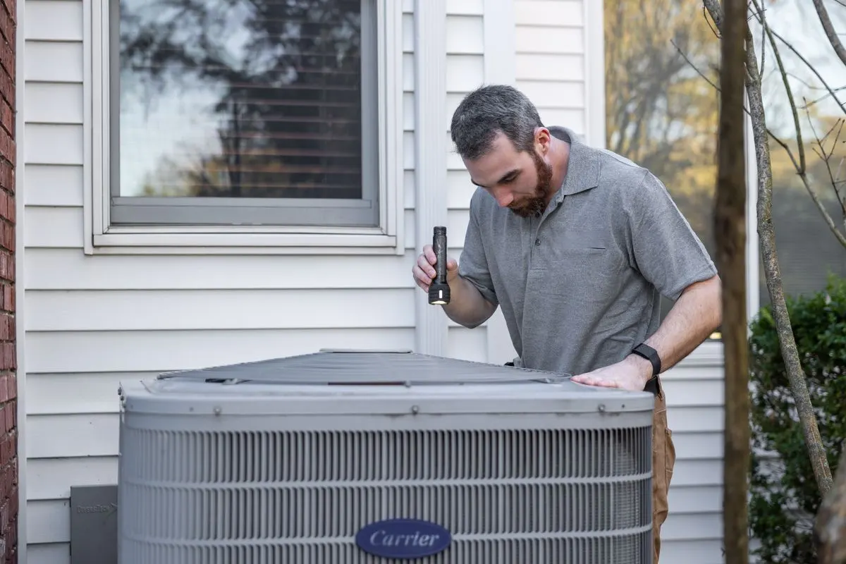 HVAC technician inspecting an outdoor mini split condenser unit